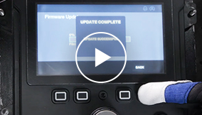 Closeup of a screen interface and a finger pushing a button below the screen, with a play button on the image
